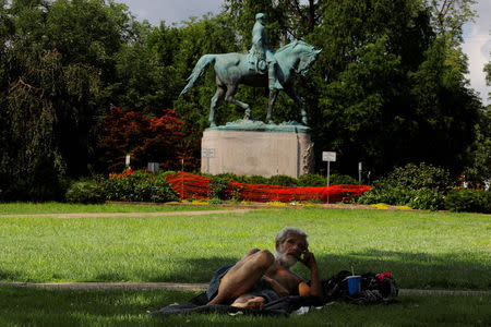 A homeless man lies in the park in front the statue of Confederate Civil War General Robert E. Lee, ahead the one-year anniversary of the fatal white-nationalist rally, in Charlottesville, Virginia, U.S., July 31, 2018. REUTERS/Brian Snyder