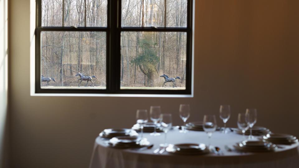 A view from a window at Horse Feathers Kitchen and Cocktails and The Reserve Events Center, expected to open in May 2024, shows bronze horse statues running along the woods of the Putnam Township property, which was once part of Girl Scout camp Camp Innisfree.