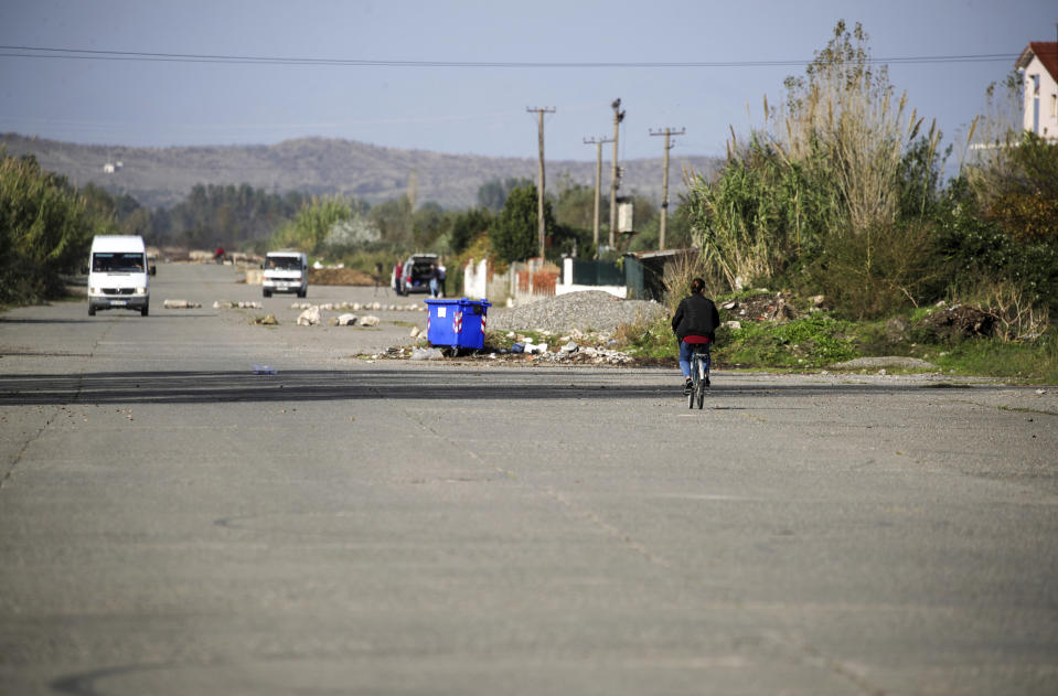 A woman rides a bicycle on a former runaway of a military airport, now used as a road, in Gjader, northwestern Albania, on Tuesday, Nov. 7, 2023. Italian Premier Giorgia Meloni announced that Albania had agreed to give temporary shelter to thousands of migrants who try to reach Italian shores while their asylum bids are being processed. Albania will offer two facilities, a quarantine area at the port of Shengjin and an accommodation center for those who will be deported at a former military airport in Gjader. (AP Photo/Armando Babani)