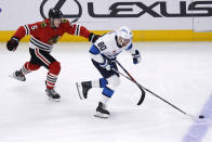 Winnipeg Jets left wing Pierre-Luc Dubois, right, chases the puck next to Chicago Blackhawks defenseman Connor Murphy during the third period of an NHL hockey game in Chicago, Friday, Dec. 9, 2022. The Jets won 3-1. (AP Photo/Nam Y. Huh)