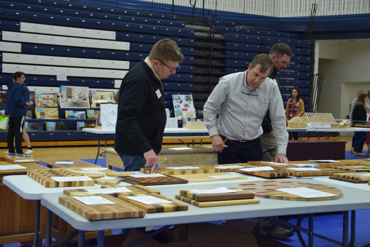 Judges look at the cutting board submission at the regional MITES competition May 5 at Petoskey High School.