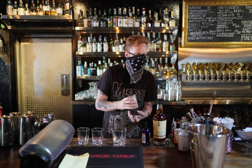 FILE - In this July 10, 2020, file photo, Davey Francis mixes drinks at Velveteen Rabbit, a cocktail bar in the Las Vegas Arts District, on the last night before they will have to close in Las Vegas. Bars in and around Las Vegas can reopen after this weekend with limited capacity, distance between customers and facial coverings all around, officials announced Thursday, Sept. 17, 2020. (AP Photo/John Locher, File)