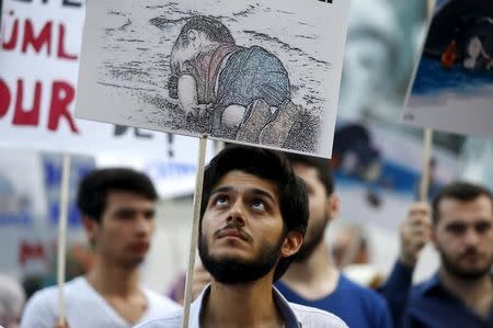 A man holds a poster with a drawing depicting a drowned Syrian toddler during a demonstration for refugee rights in Istanbul, Turkey, September 3, 2015. REUTERS/Osman Orsal