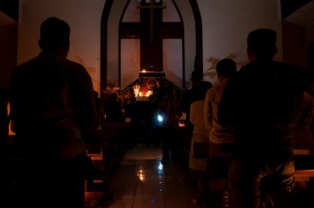 Christian worshippers are illuminated by candlelight as they attend a mass during a major power blackout at a church in Bandung