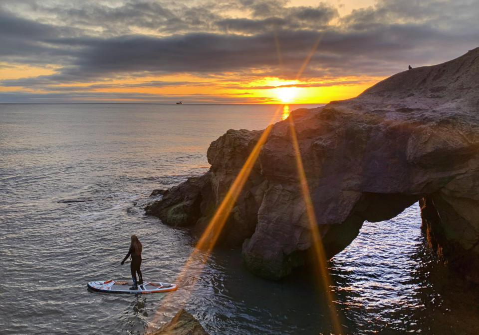 Anna Heslop, 25, paddleboarding during sunrise at Cullercoats Bay on the North East coast. Picture date: Tuesday March 30, 2021. Temperatures in parts of the UK are expected to be significantly warmer this week as families and friends are reunited and sporting activities are allowed to resume in England.