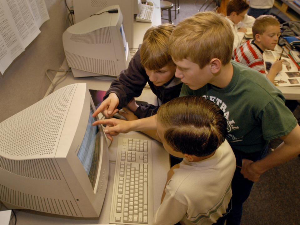 Students point at a computer screen in 2003
