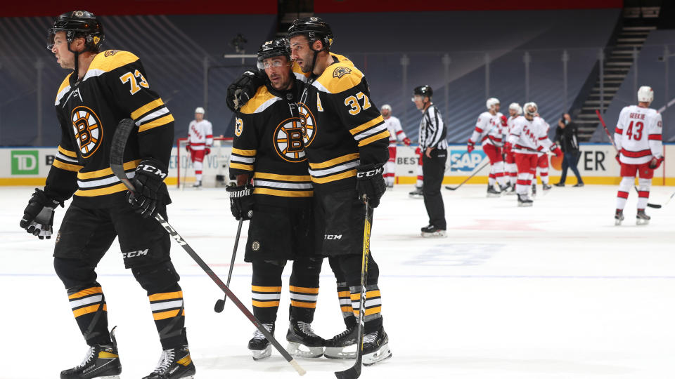 TORONTO, ONTARIO - AUGUST 19:  Brad Marchand #63, Patrice Bergeron #37 and Charlie McAvoy #73 of the Boston Bruins celebrates after their team defeated the Carolina Hurricanes 2-1 to clinch the series 4-1 after Game Five of the Eastern Conference First Round during the 2020 NHL Stanley Cup Playoffs at Scotiabank Arena on August 19, 2020 in Toronto, Ontario. (Photo by Chase Agnello-Dean/NHLI via Getty Images)