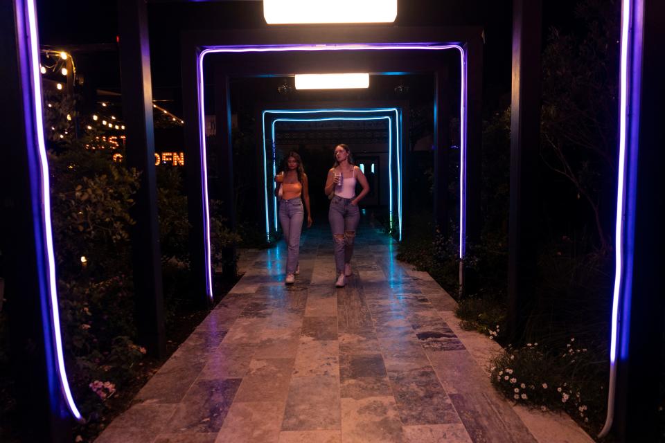 Customers Asha Chechani and Victoria Haines walk under LED arches at the Austin Gardens & Studio on Friday.