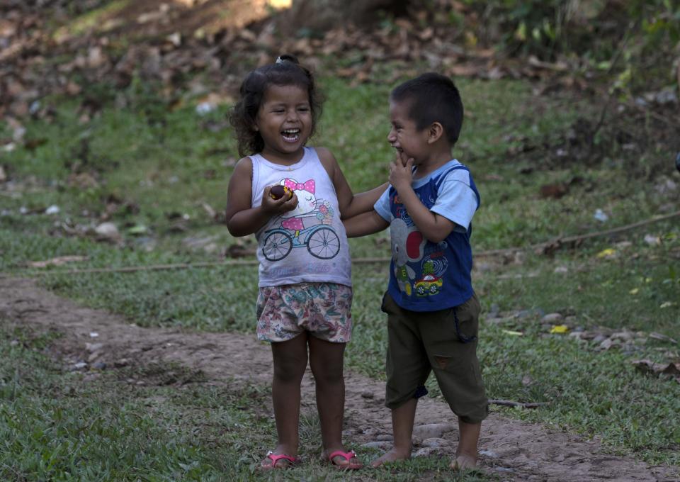 Children laugh while eating a local fruit in the Chambira community, in Peru's Amazon, Tuesday, Oct. 4, 2022. Residents in Kichwa Indigenous villages in Peru say they fell into poverty after the government turned their ancestral forest into a national park, restricted hunting and sold forest carbon credits to oil companies. (AP Photo/Martin Mejia)