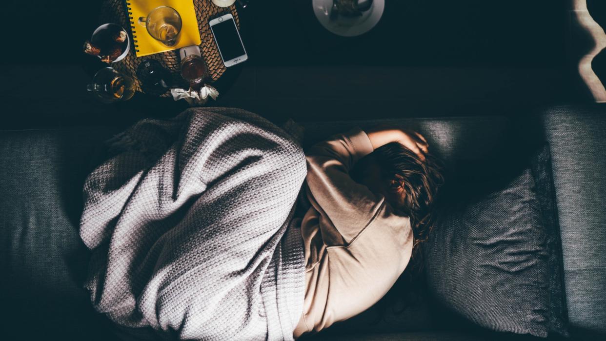  Sad woman lying on sofa at home. 