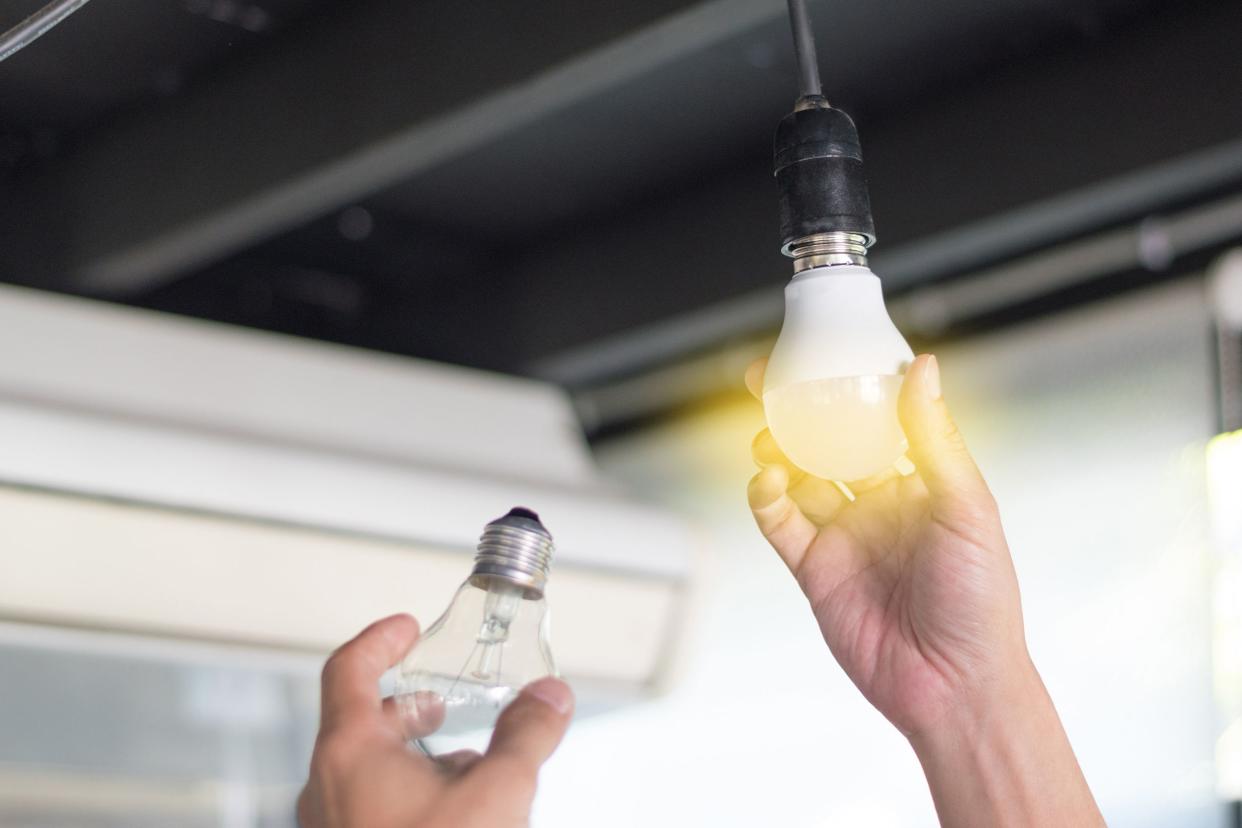 man changing compact-fluorescent (CFL) bulbs with new LED light bulb