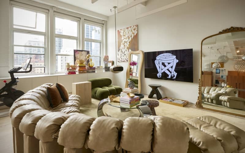 Wall mounted television in eclectic living room with semi-circular sofa.