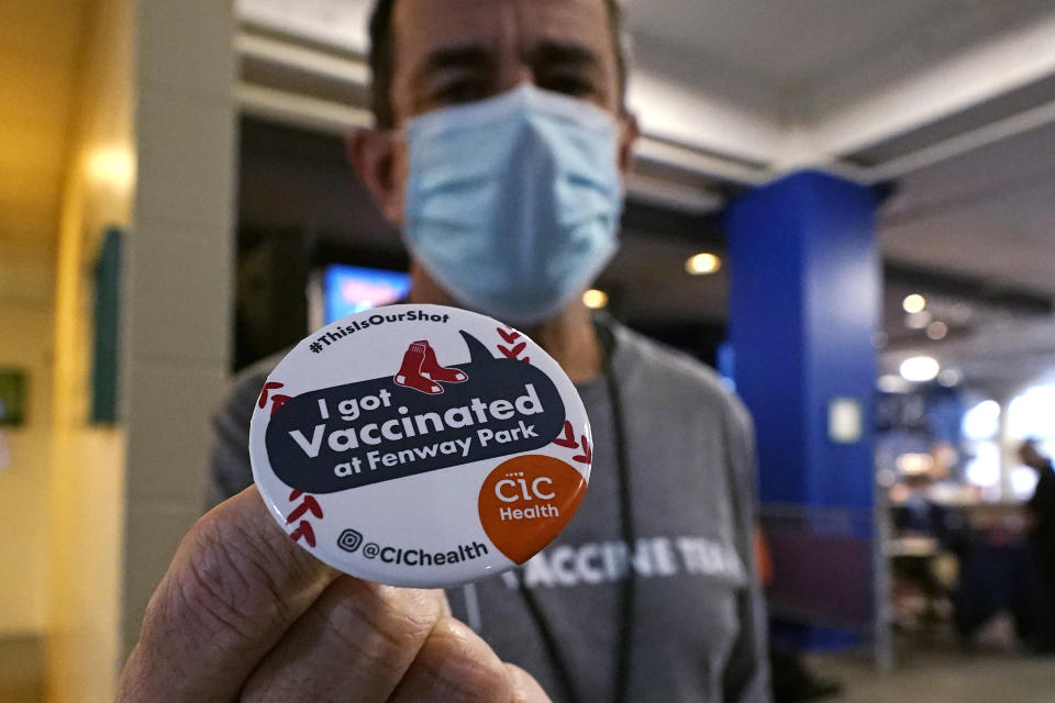 Boston Marathon Race Director Dave McGillivray holds an "I Got Vaccinated" button at a COVID-19 vaccine injection site set in a concession area at Fenway Park, Thursday, Jan. 28, 2021, in Boston. Since the 2021 Boston Marathon is on hold until fall, McGillivray has been tapped by the state of Massachusetts to run mass vaccination operations at Gillette Stadium and Fenway Park. Event organizers and other unconventional logistics experts are using their skills to help the nation vaccinate as many people as possible. (AP Photo/Charles Krupa)