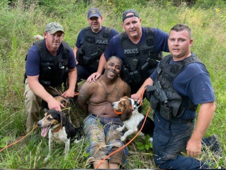 <p>Anger as armed white police officers with dogs pose with captured Black suspect</p> (Prentiss Police Department )