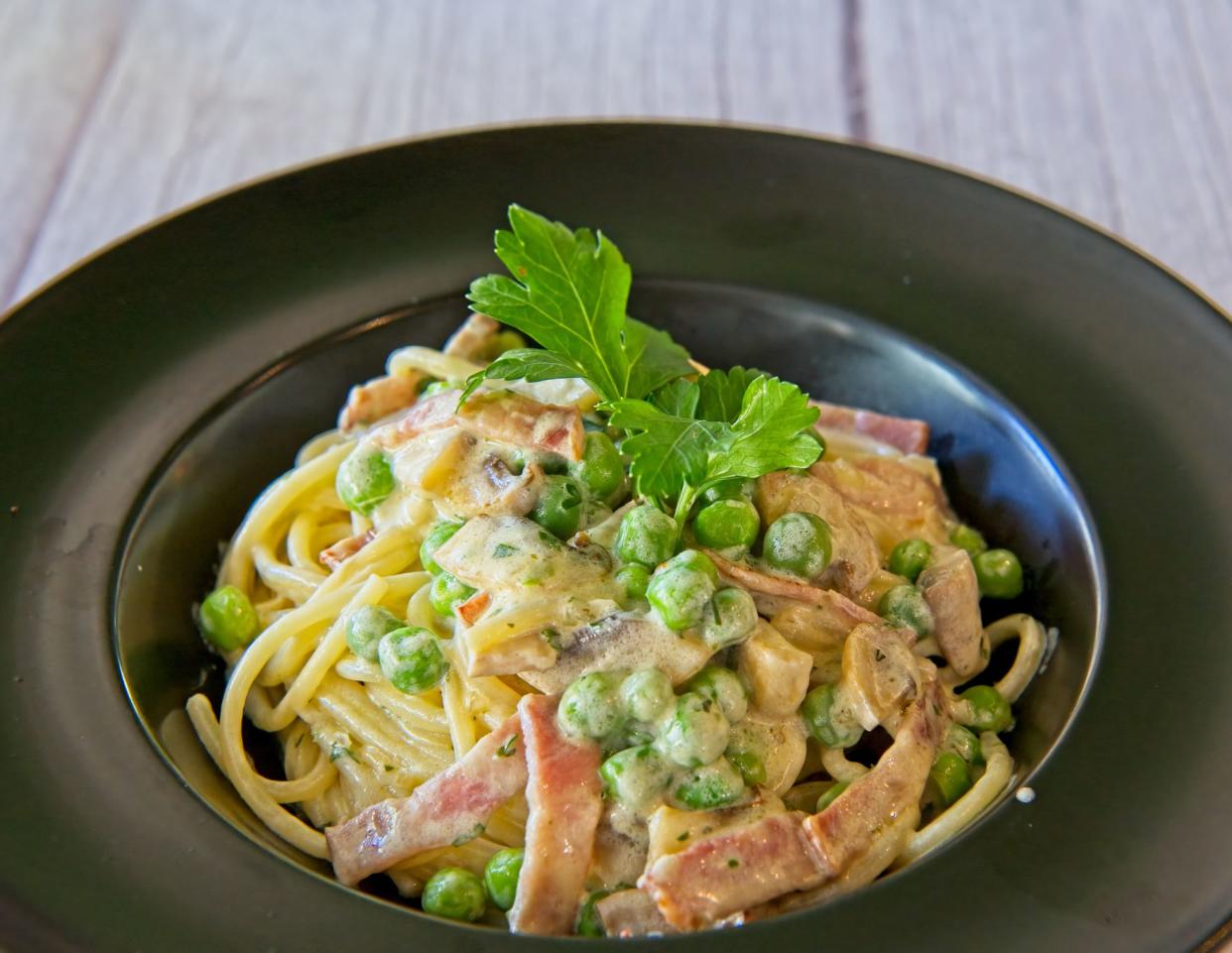 Tasty creamy pasta with bacon and green peas.
