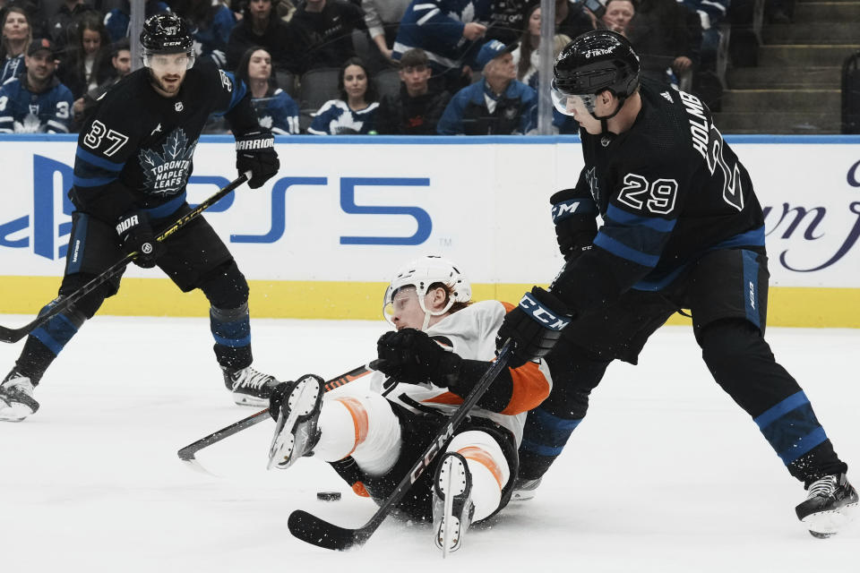 Philadelphia Flyers right wing Owen Tippett (74) falls to the ice as he battles for the puck against Toronto Maple Leafs right wing Pontus Holmberg (29) during the third period of an NHL hockey game, Thursday, Dec. 22, 2022 in Toronto. (Chris Young/The Canadian Press via AP)