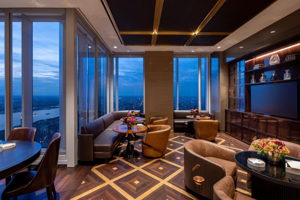 a room with chairs and floor-to-ceiling windows seen at night on the 100th floor of luxury skyscraper Central Park Tower