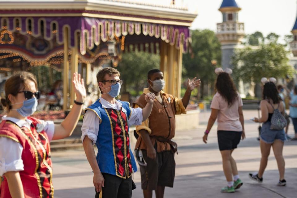 In this handout photo provided by Walt Disney World Resort, Disney cast members welcome guests to Magic Kingdom Park at Walt Disney World Resort