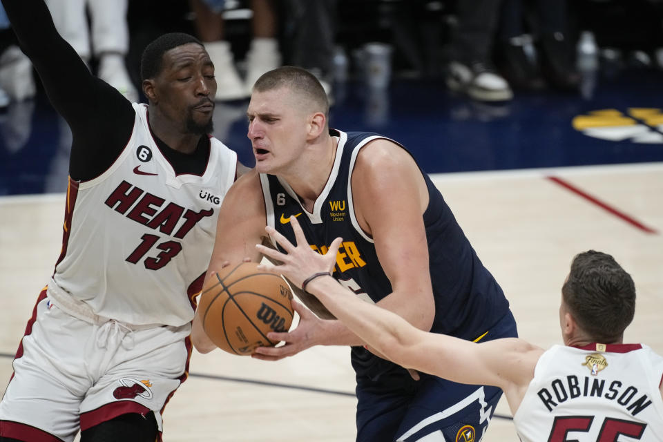 Denver Nuggets center Nikola Jokic, center, tries to get past Miami Heat center Bam Adebayo (13) during the second half of Game 2 of basketball's NBA Finals, Sunday, June 4, 2023, in Denver. (AP Photo/David Zalubowski)