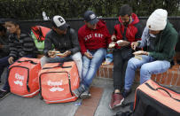 Venezuelan bicycle courier Samuel Romero, second from right, and fellow Venezuelan couriers make sandwiches as they wait for delivery orders through Rappi in Bogota, Colombia, Monday, July 8, 2019. Cyclists in Colombia complain that payments are falling as more freelancers join the platform and compete for each delivery, forcing them to work longer hours to make similar or even smaller amounts of money. (AP Photo/Fernando Vergara)