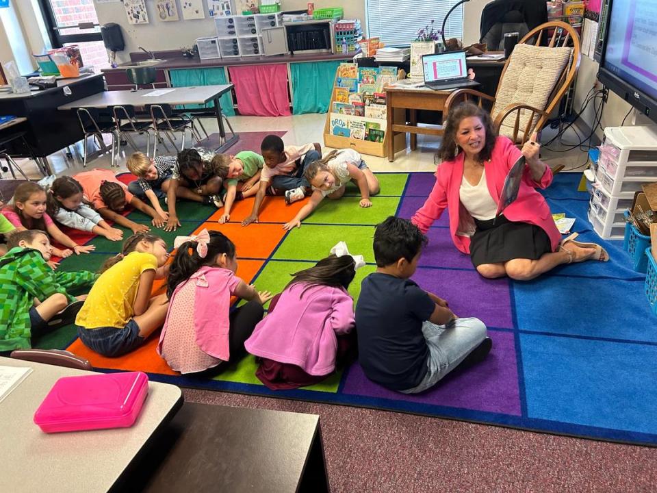State Rep. Donna White has first-grade students stretch their hands to the floor as she reads them “Three Hens And A Peacock” at Riverwood Elementary School in Clayton, N.C., for Bring Your Legislator To School Day on May 15, 2023,