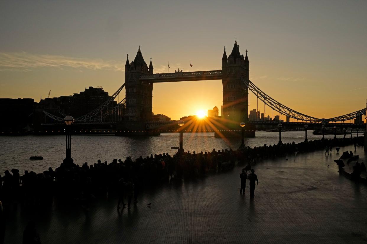 The sun rises as people line up near the Tower Bridge to pay their respects to the late Queen Elizabeth II during the Lying-in State, in Westminster Hall, in London, England, Saturday, Sept. 17, 2022. Thousands of people spent London's coldest night in months huddled in line to view the coffin of Queen Elizabeth II, and authorities warned Saturday that arriving mourners face a 24-hour wait. (AP Photo/Kin Cheung)