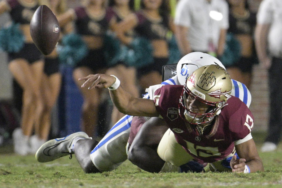 Florida State quarterback Jordan Travis (13) flips the ball to a receiver as he is brought down by Duke defensive end Wesley Williams during the first half of an NCAA college football game, Saturday, Oct. 21, 2023, in Tallahassee, Fla. Travis was ruled down on the play after a review. (AP Photo/Phelan M. Ebenhack)