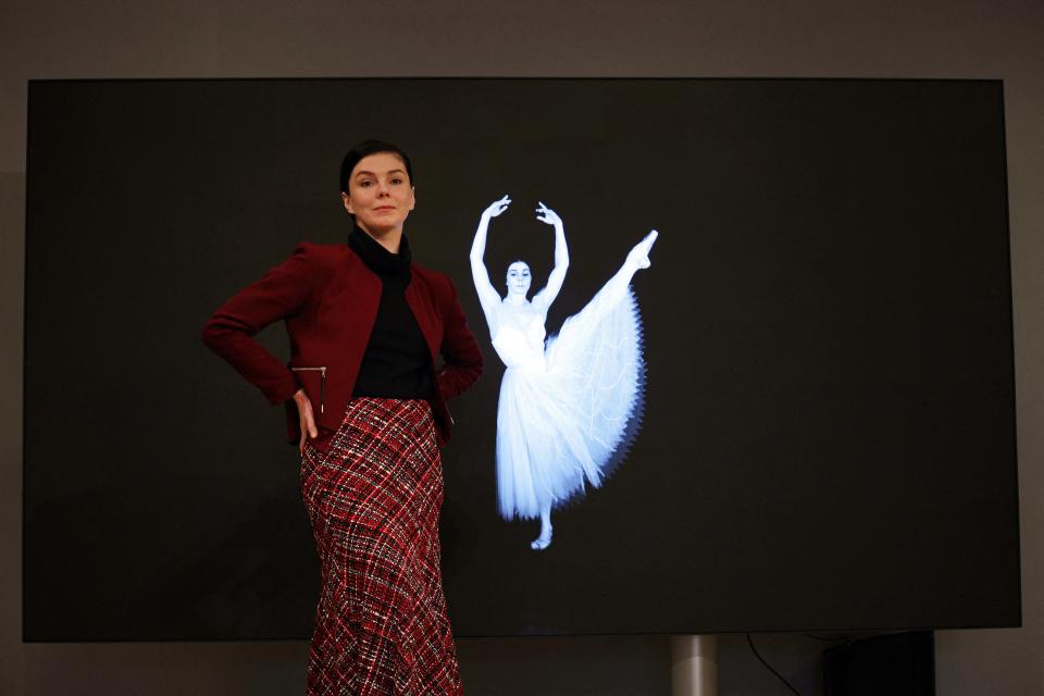 Ballet dancer Natalia Osipova poses beside a screen showing a freeze-frame image from a dance performance video at Bonhams in London on November 29, 2021. - Bonhams are to offer the world's first ballet NFT (non-fungible tokens) entitled: 