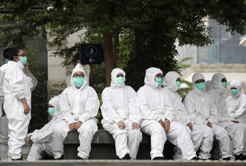Medical workers take a break at a coronavirus mobile test site in Jakarta, Indonesia, Wednesday, May 6, 2020. The Indonesian Election Commission has decided to postpone preparations for Sept. 23, 2020, regional elections until at least December later this year after a number of organizers got sick with virus. (AP Photo/Dita Alangkara)