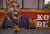 A child poses for pictures next to a mural of former NBA star Kobe Bryant outside the "House of Kobe" basketball court on Jan. 28, 2020 in Valenzuela, Metro Manila, Philippines. (Credit: Ezra Acayan/Getty Images)