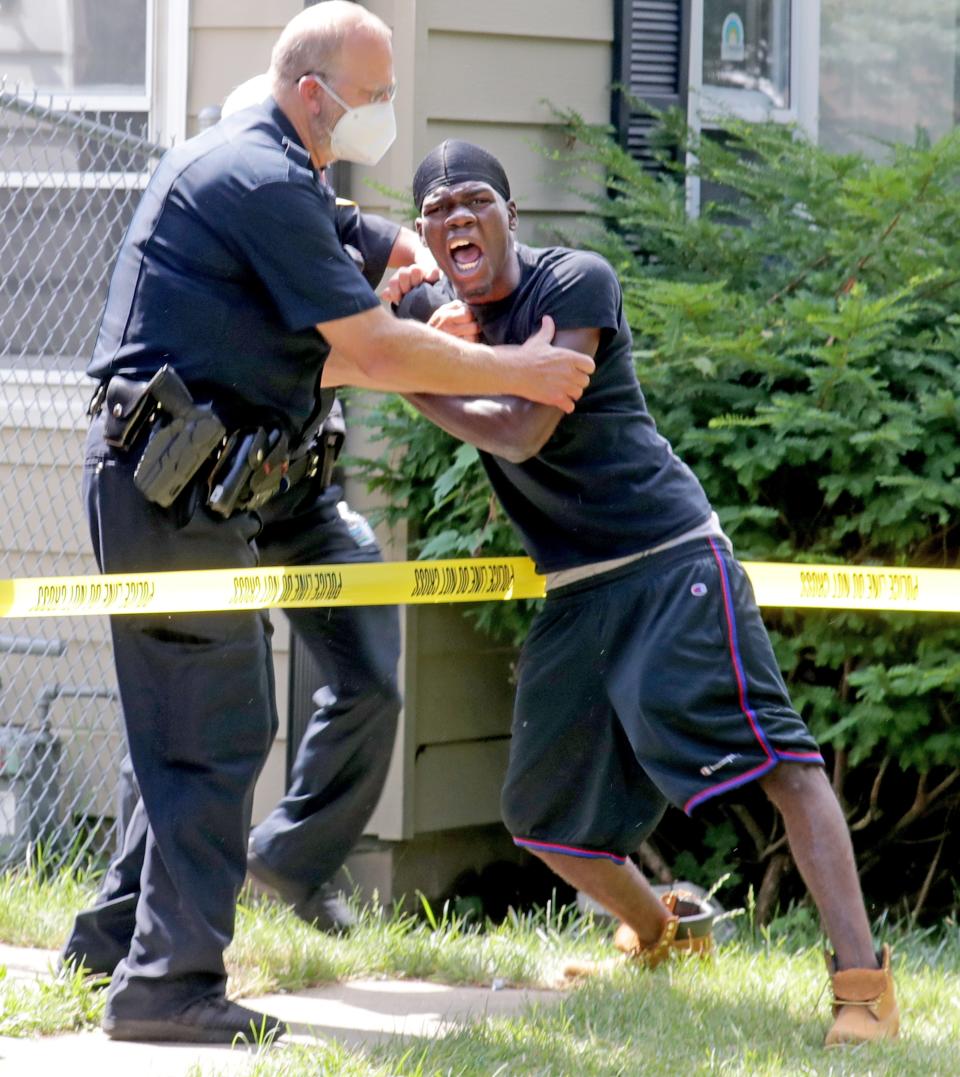 A man overcome with emotion tries to get past police as an investigation takes place at a reported homicide in an alley on North 65th Street just north of West Silver Spring Drive in Milwaukee on Wednesday, July 8, 2020.
