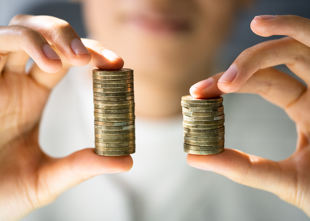 Hands holding unequal stacks of coins.