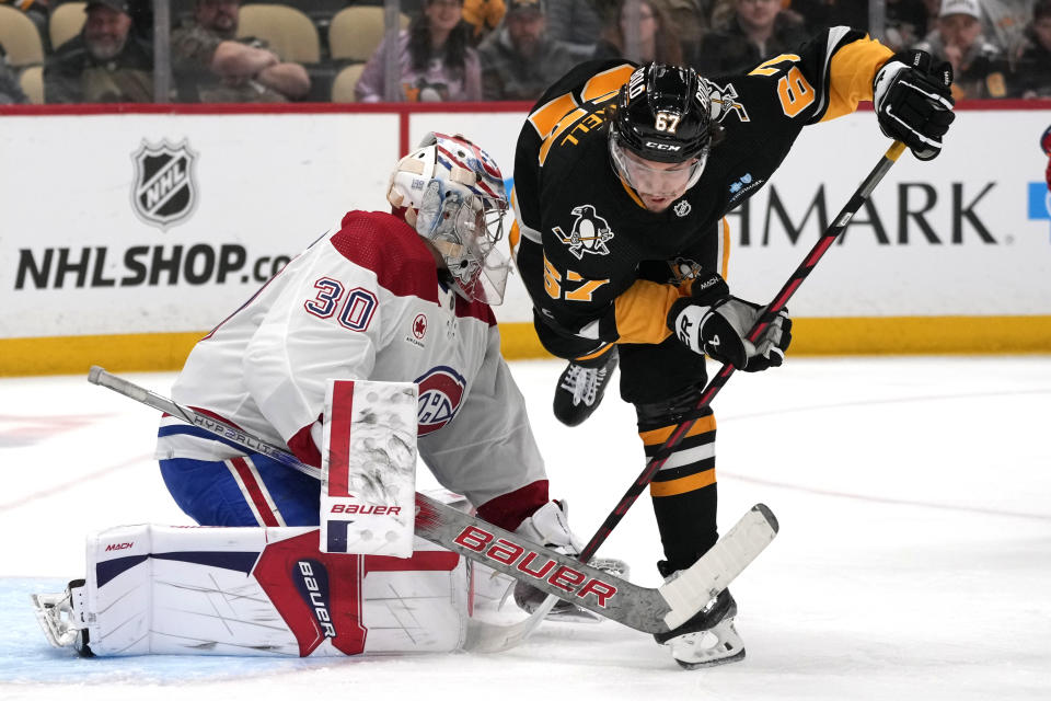 Pittsburgh Penguins' Rickard Rakell (67) trips over the stick of Montreal Canadiens goaltender Cayden Primeau during the second period of an NHL hockey game in Pittsburgh, Thursday, Feb. 22, 2024. (AP Photo/Gene J. Puskar)