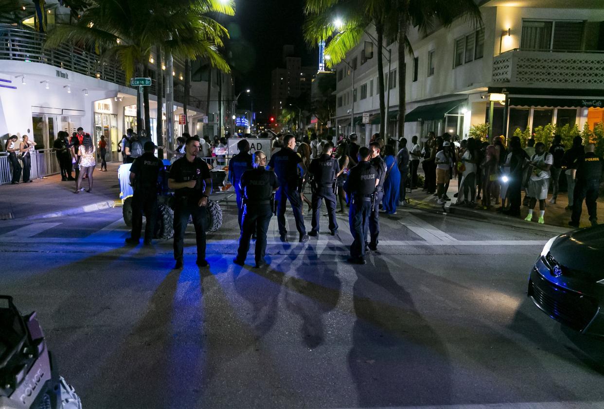 A group of police officers gather on Ocean Drive and 8th Street in Miami Beach, Fla., Friday, March 25, 2022. City officials imposed a midnight curfew and forced stores to stop selling alcohol after 6 p.m. The restrictions were set in place after two shootings in Miami Beach the weekend before caused city officials to announce a "state of emergency." (Matias J. Ocner/Miami Herald via AP)