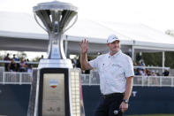 Jason Kokrak waves to the gallery while standing near the trophy during ceremonies after winning the Houston Open golf tournament Sunday, Nov. 14, 2021, in Houston. (AP Photo/Michael Wyke)