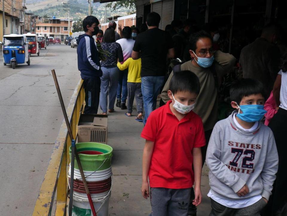 Children wearing masks walk outside a cemetery in Cajamarca, Peru, on May 9, 2021.