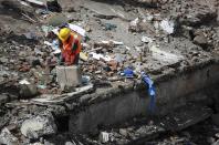 A rescue worker holds a suitcase of a resident at the site of a collapsed residential building in Mumbai September 27, 2013. (REUTERS/Danish Siddiqui)