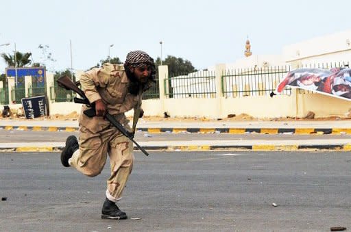 A Libyan rebel fighter runs for cover as Moamer Kadhafi's loyalist forces pummel their positions with rocket fire at a gate of the north-central key Libyan oil town of Ras Lanuf