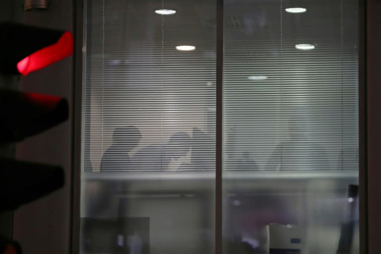 The silhouettes of people are seen inside the offices of Cambridge Analytica in London on March 23, 2018, just hours after a judge approved a search warrant of the offices
