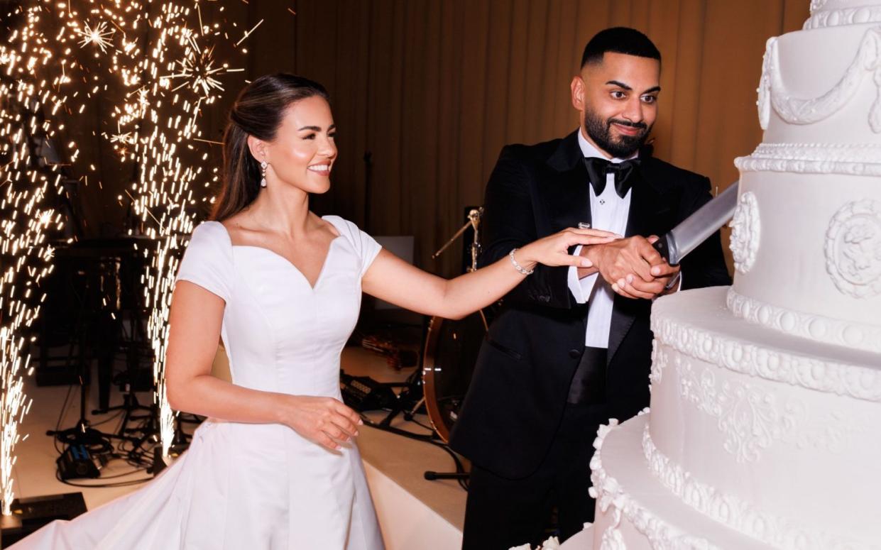 Nada and Umar Kamani cut a huge, white cake, with a large knife