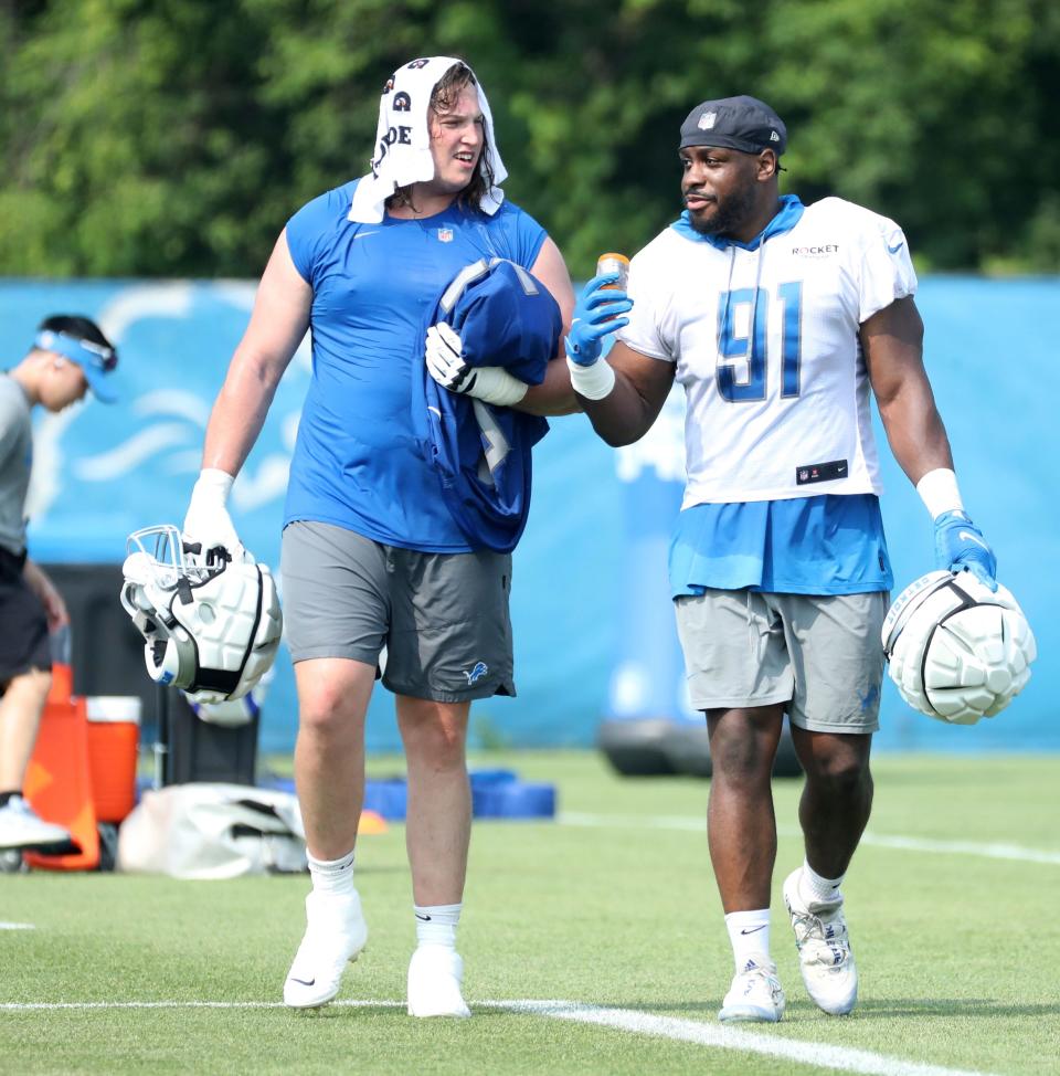 Detroit Lions offensive lineman Colby Sorsdal, left, and defensive end Levi Onwuzurike walk off the field after training camp in Allen Park, Tuesday, July 25, 2023.