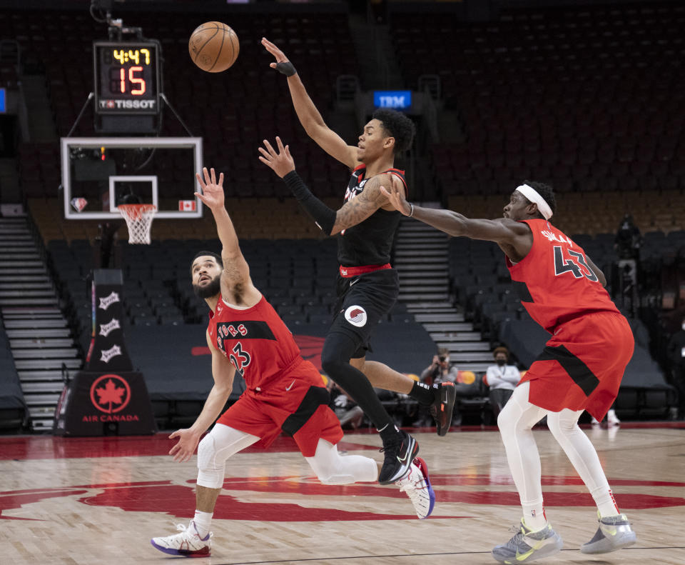 Portland Trail Blazers guard Anfernee Simons, center, passes the ball under pressure from Toronto Raptors forward Pascal Siakam (43) and guard Fred VanVleet (23) during second-half NBA basketball game action in Toronto, Sunday Jan. 23, 2022. (Frank Gunn/The Canadian Press via AP)