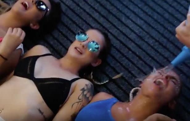 There's a video with Blake which opens with a group of men gathered around bikini-clad women lying down on the ground, before one bloke takes the liberty to pour some drinks into their mouths. Source: Blake Colman/Youtube