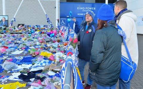 Leicester City fans inspect the memorial left outside of the King Power Stadium ahead of the club's match against Cardiff City today - Credit: Plumb Images/Leicester City FC