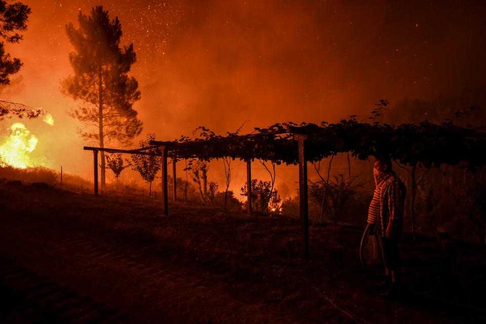 A villages holds a hose as a wildfire comes close to his house at Amendoa in Macao, central Portugal on July 21, 2019. (Photo: Patricia De Melo Moreira/AFP/Getty Images)