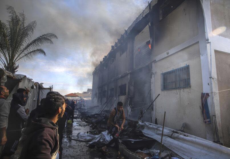 Palestinians try to extinguish a fire at a building of an UNRWA vocational training center which displaced people use as a shelter, after being targeted by Israeli tank shill in Khan Younis, southern Gaza Strip, Wednesday, Jan. 24, 2024. (AP Photo/Ramez Habboub)