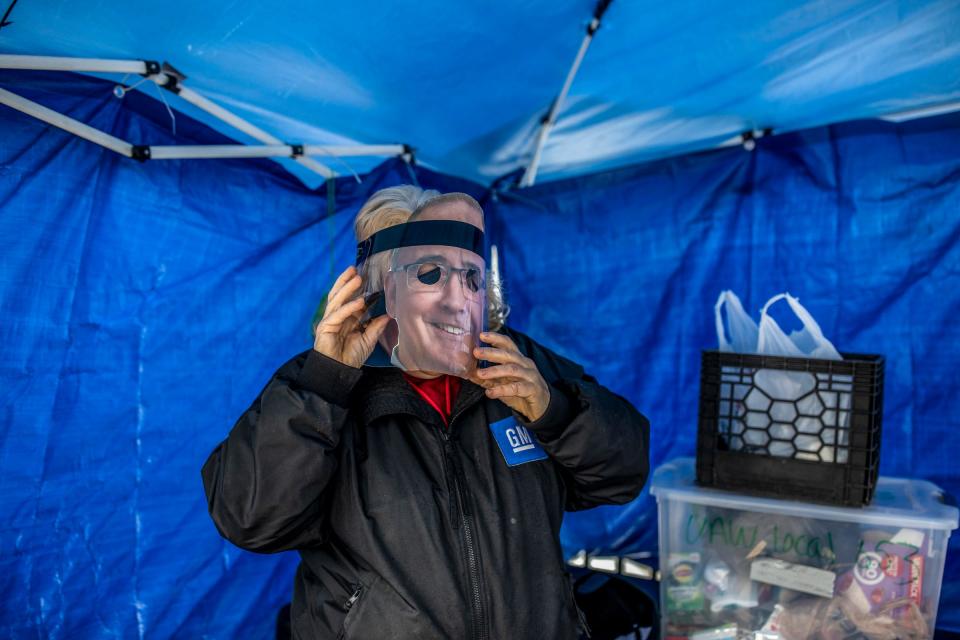 Judith Rice, 58, of Rochester, puts on a mask with Shawn Fain’s face while walking the picket line at the GM Customer Care and Aftersales plant in Pontiac, Mich., on Monday, Oct. 30, 2023. Rice says other people get to wear the superhero they look up to for Halloween and Fain is her superhero.