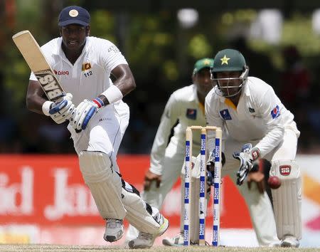 Sri Lanka's captain Angelo Mathews (L) plays a shot next to Pakistan's wicketkeeper Sarfraz Ahmed during the second day of their second test cricket match in Colombo June 26, 2015. REUTERS/Dinuka Liyanawatte