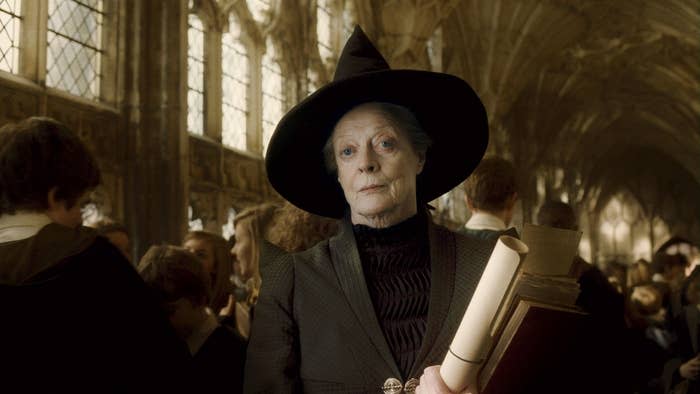 Maggie Smith as Professor McGonagall in "Harry Potter," dressed in a dark witch's hat and robe, holding scrolls in a bustling, Gothic-style hall