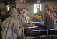 A health worker distributes food packets inside a quarantine center for COVID-19 patients, in New Delhi, India, Monday, April 19, 2021. India's health system is collapsing under the worst surge in coronavirus infections that it has seen so far. (AP Photo/Manish Swarup)